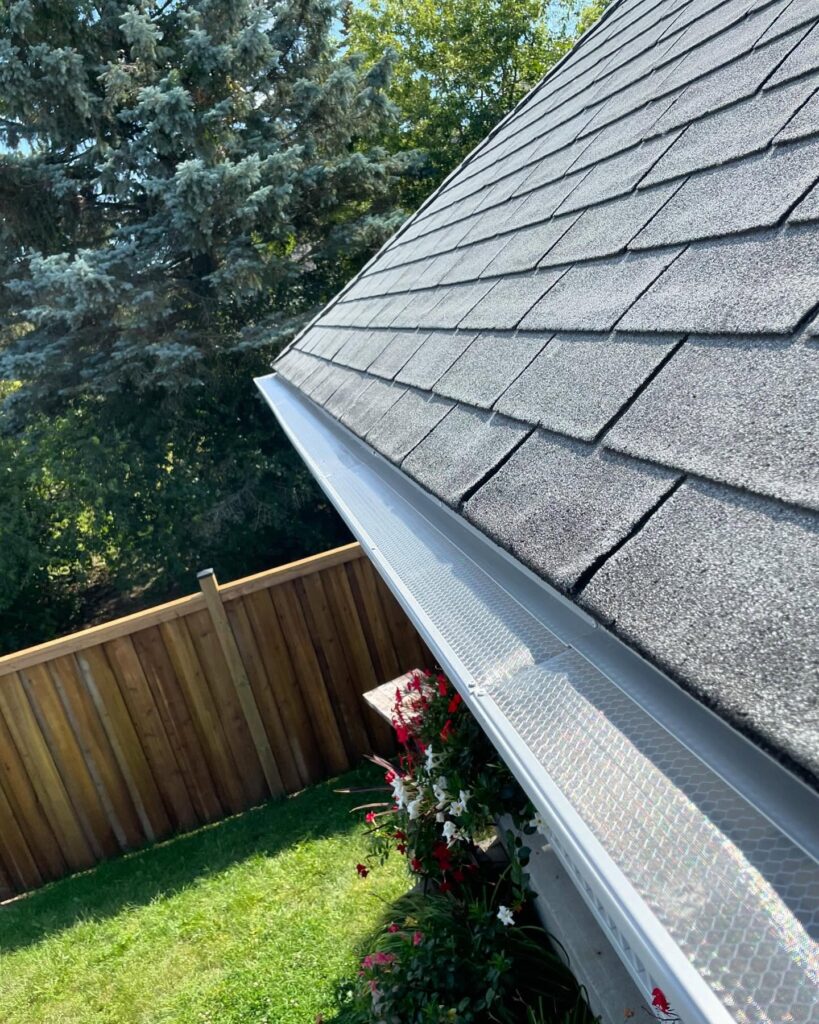Xtreme Gutter Guard on eavestroughs with wooden fence in Belleville, ON